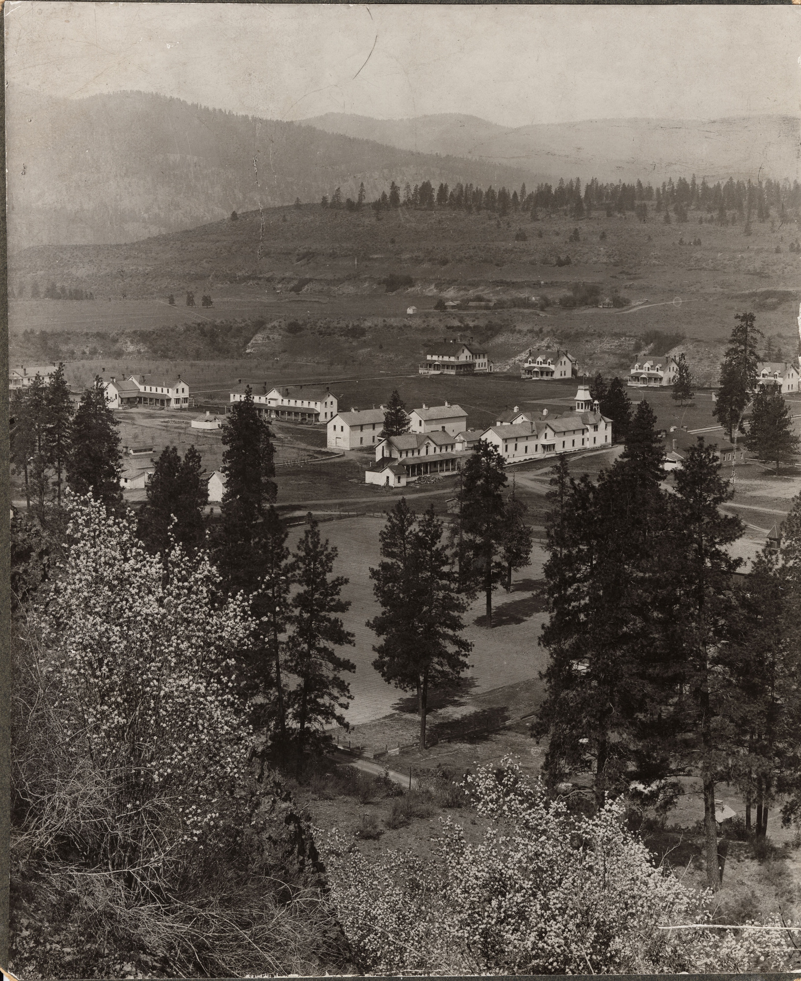 Black and white photograph of multiple multi-story white buildings in a cleared valley