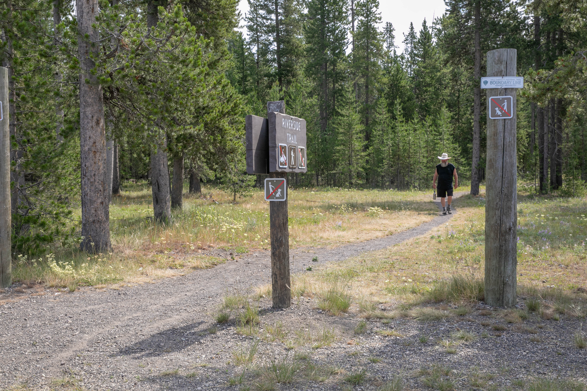 A man walks towards the camera on a flat trail.