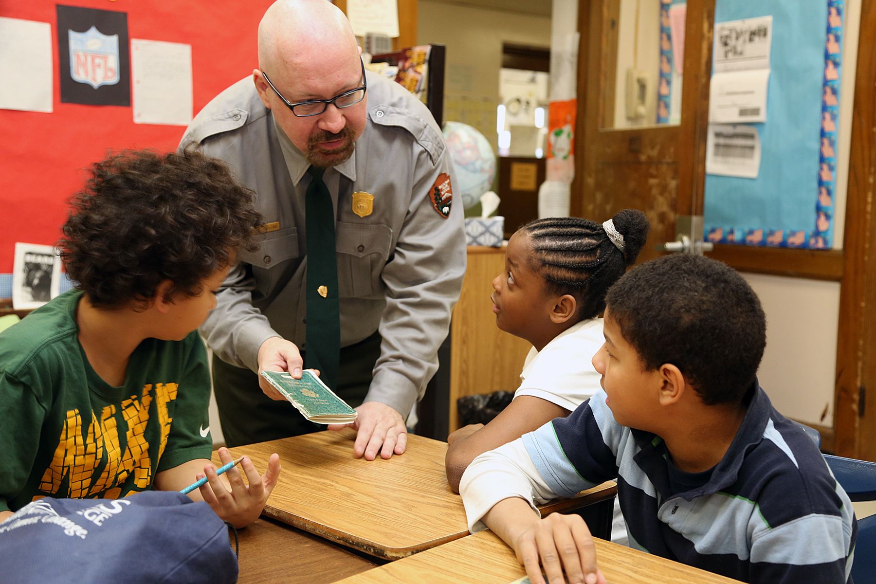 A ranger shows a document to three schoolchildren