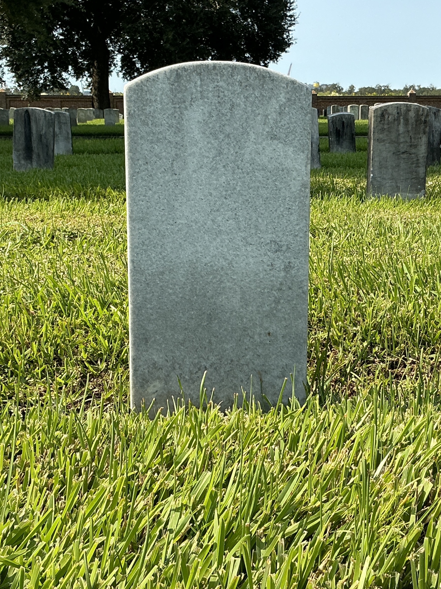 Back of historic upright marble headstone with recessed shield face.