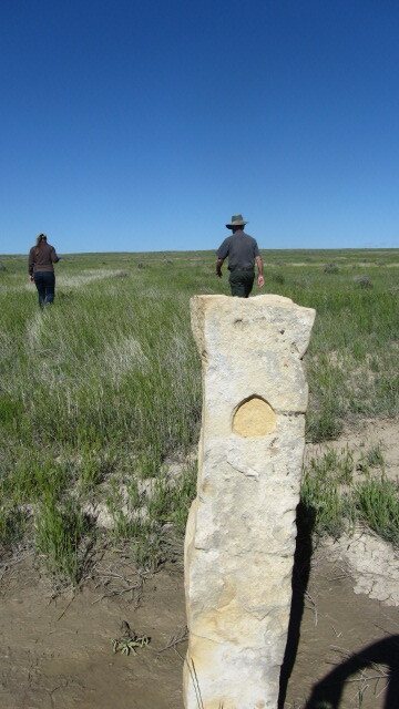 NTIR staff walking behind a limestone marker on a green grass prairie