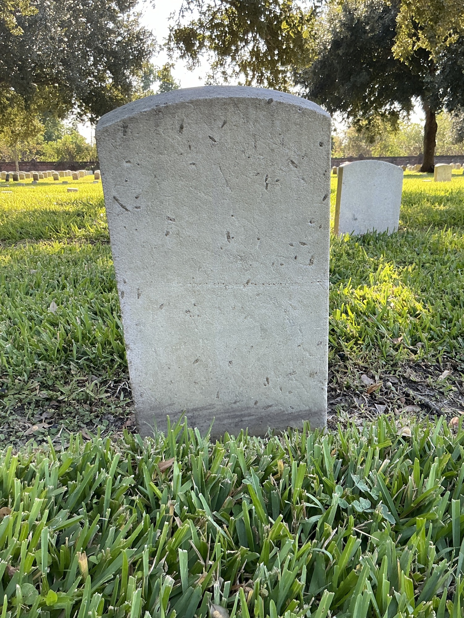 Back of historic upright marble headstone with recessed shield face.