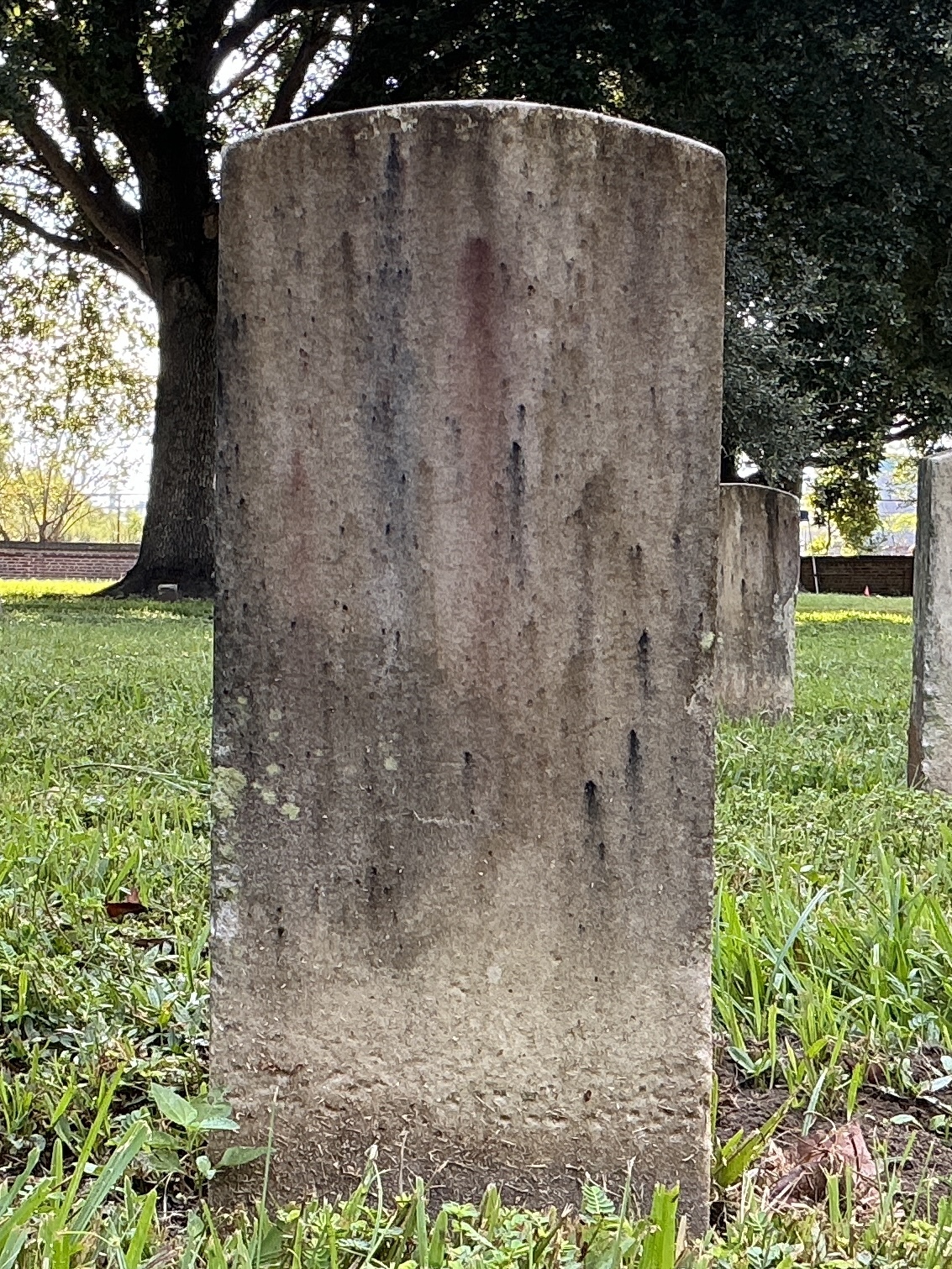 Back of historic upright marble headstone with recessed shield face.