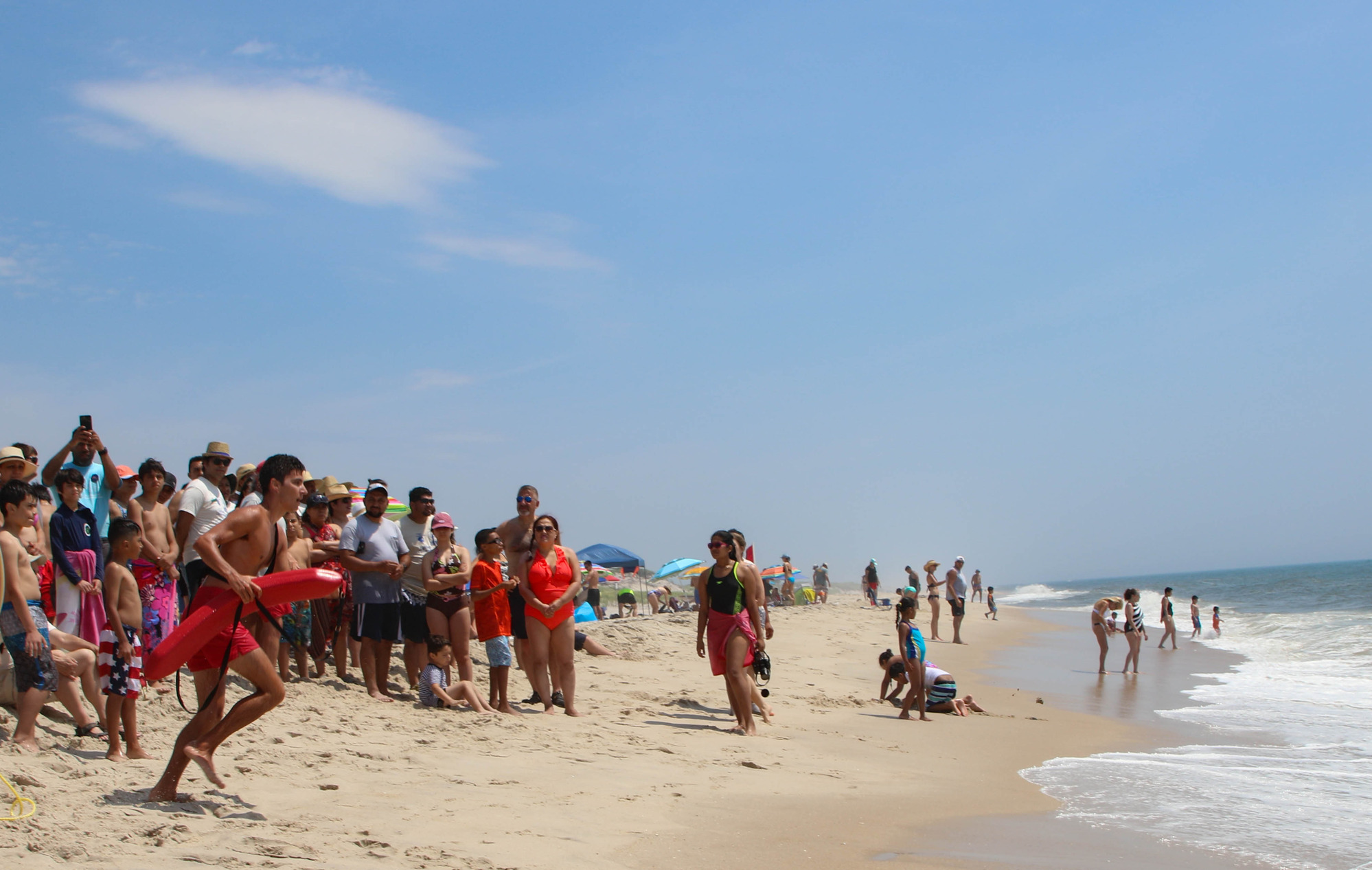 Lifeguard running toward the water in front of a crowd