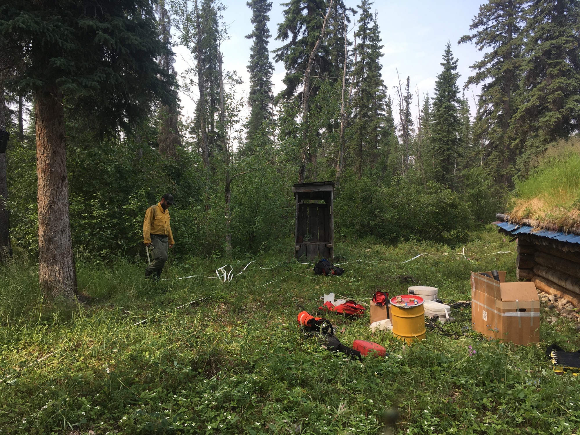 a firefighter laying out hose near a small wood cabin