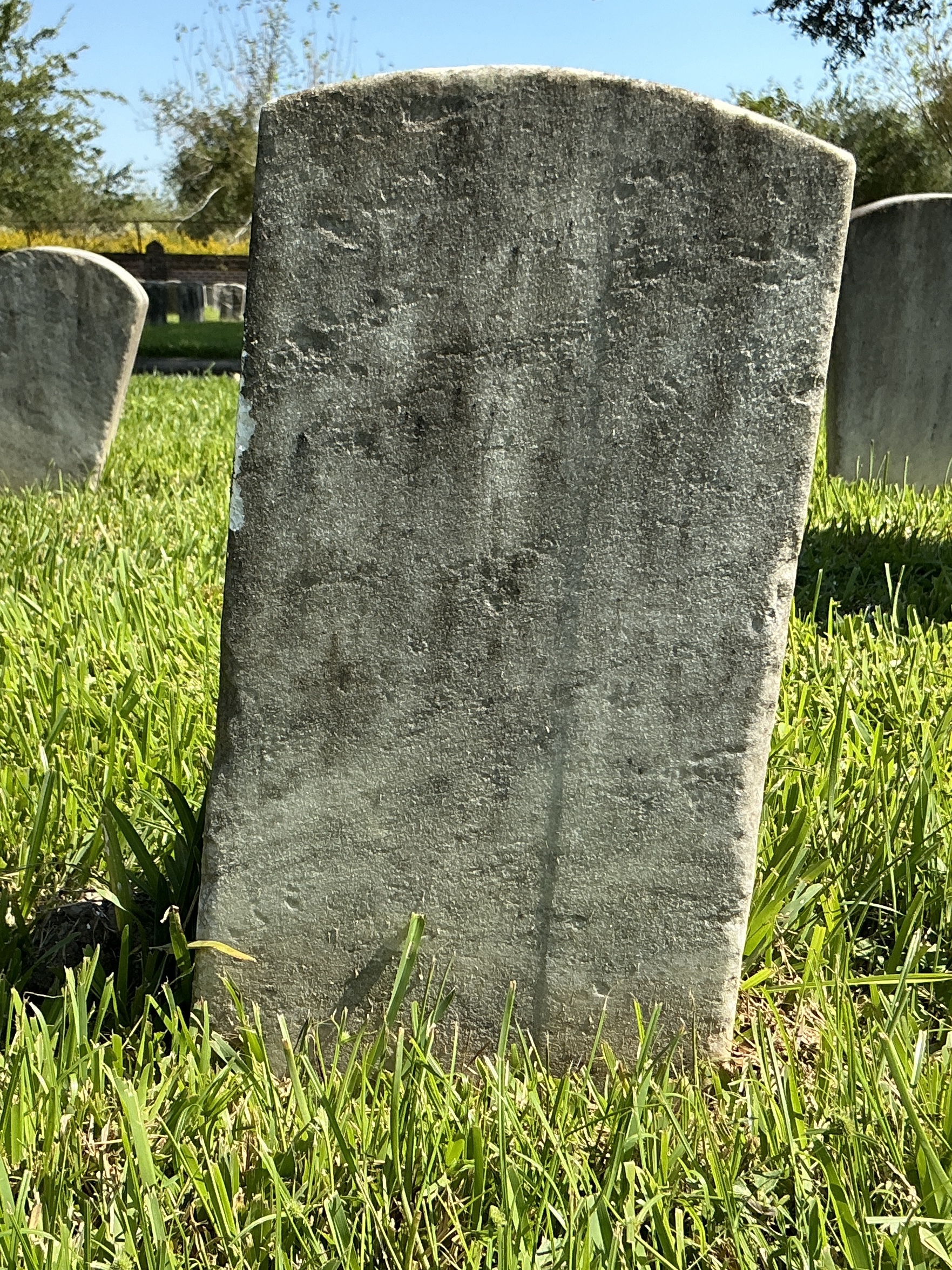 Back of historic upright marble headstone with recessed shield face.