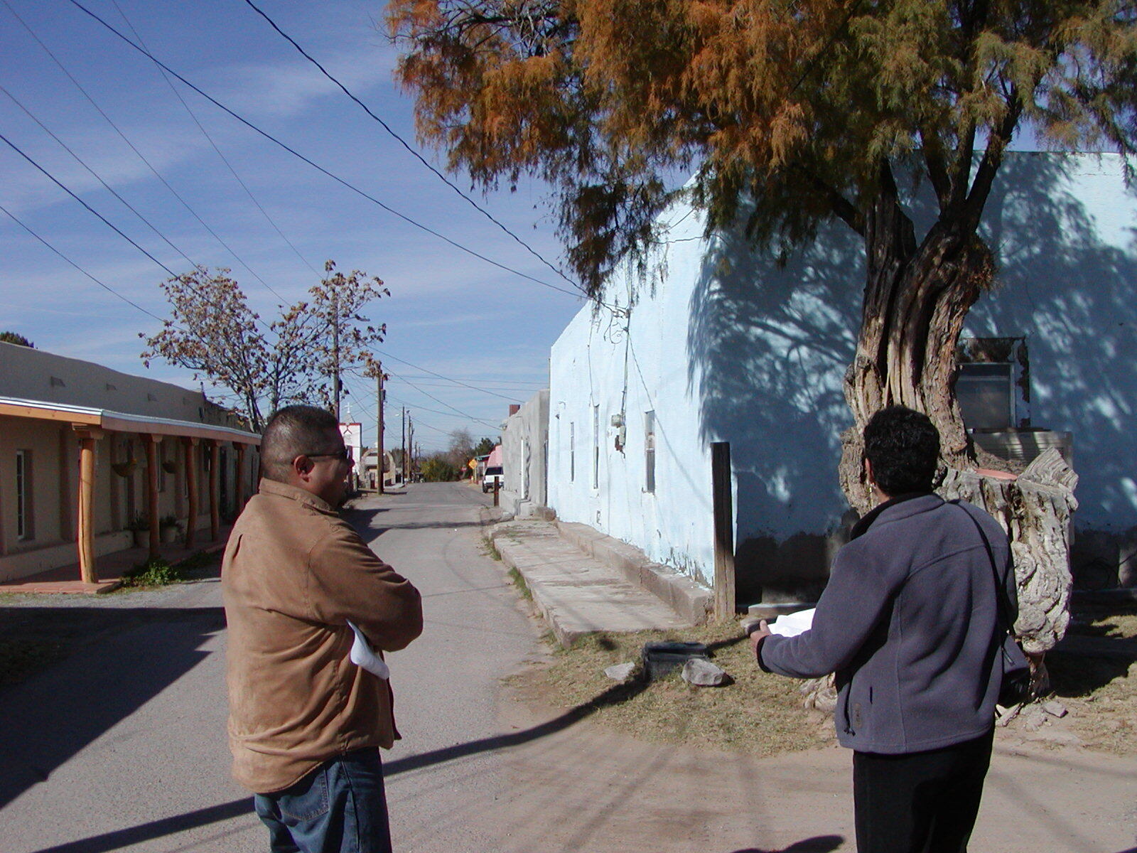 Two people standing on the side of a street.