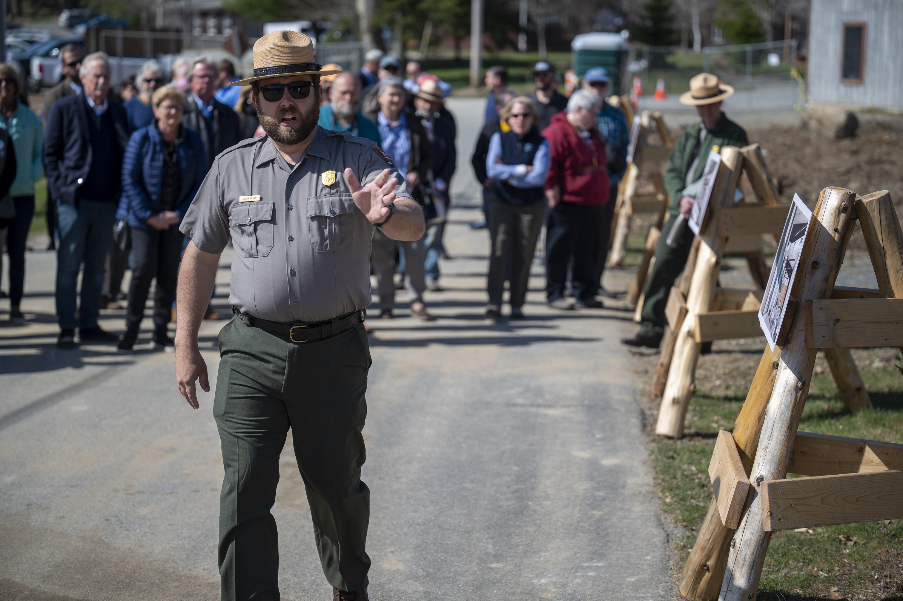 A man in ranger uniform points in front of him as he speaks. A group of people follow behind him.