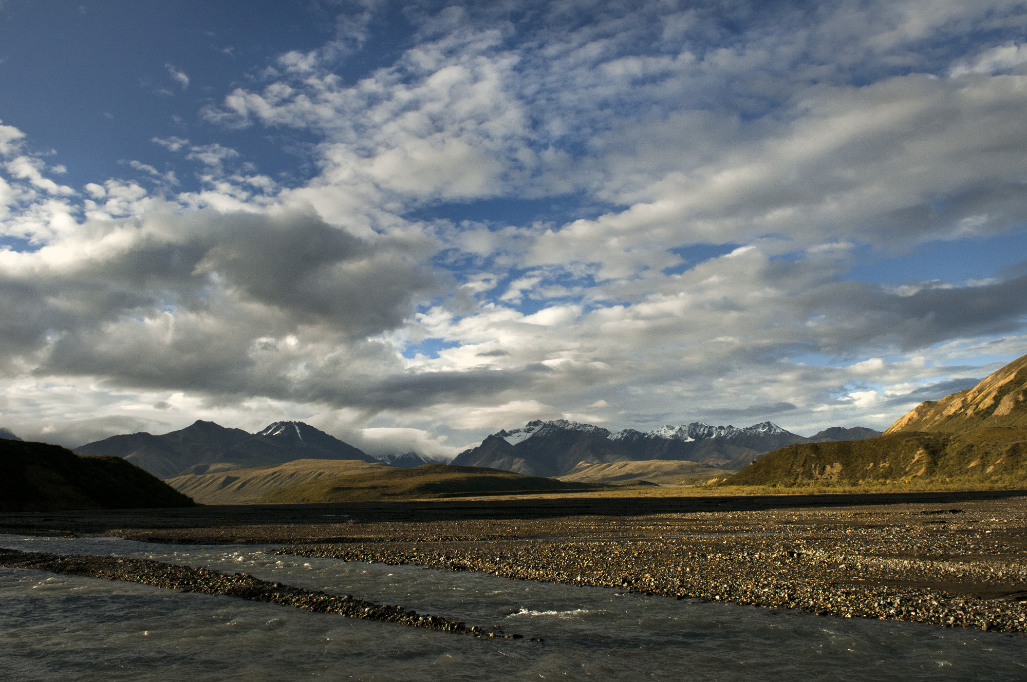 a river flowing through a wide valley between mountains