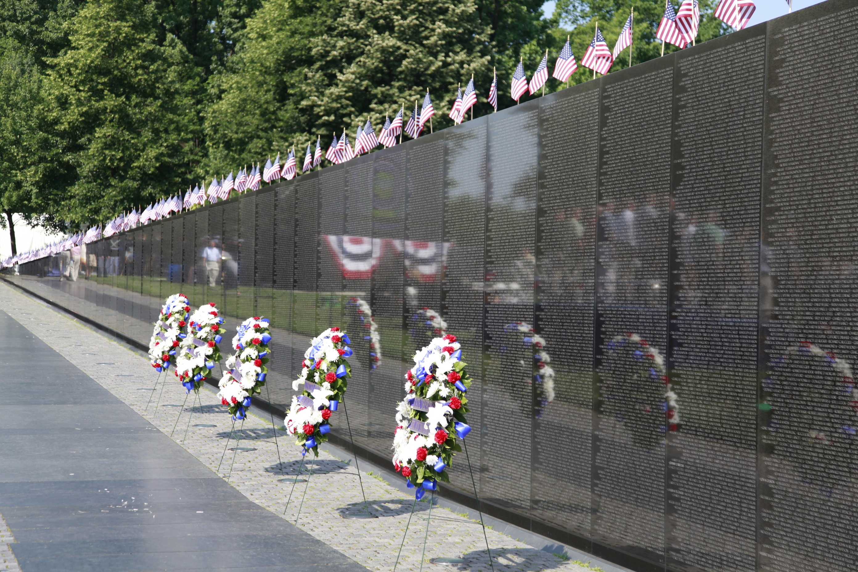 Granite wall covered in names lined with wreaths and U.S. flags