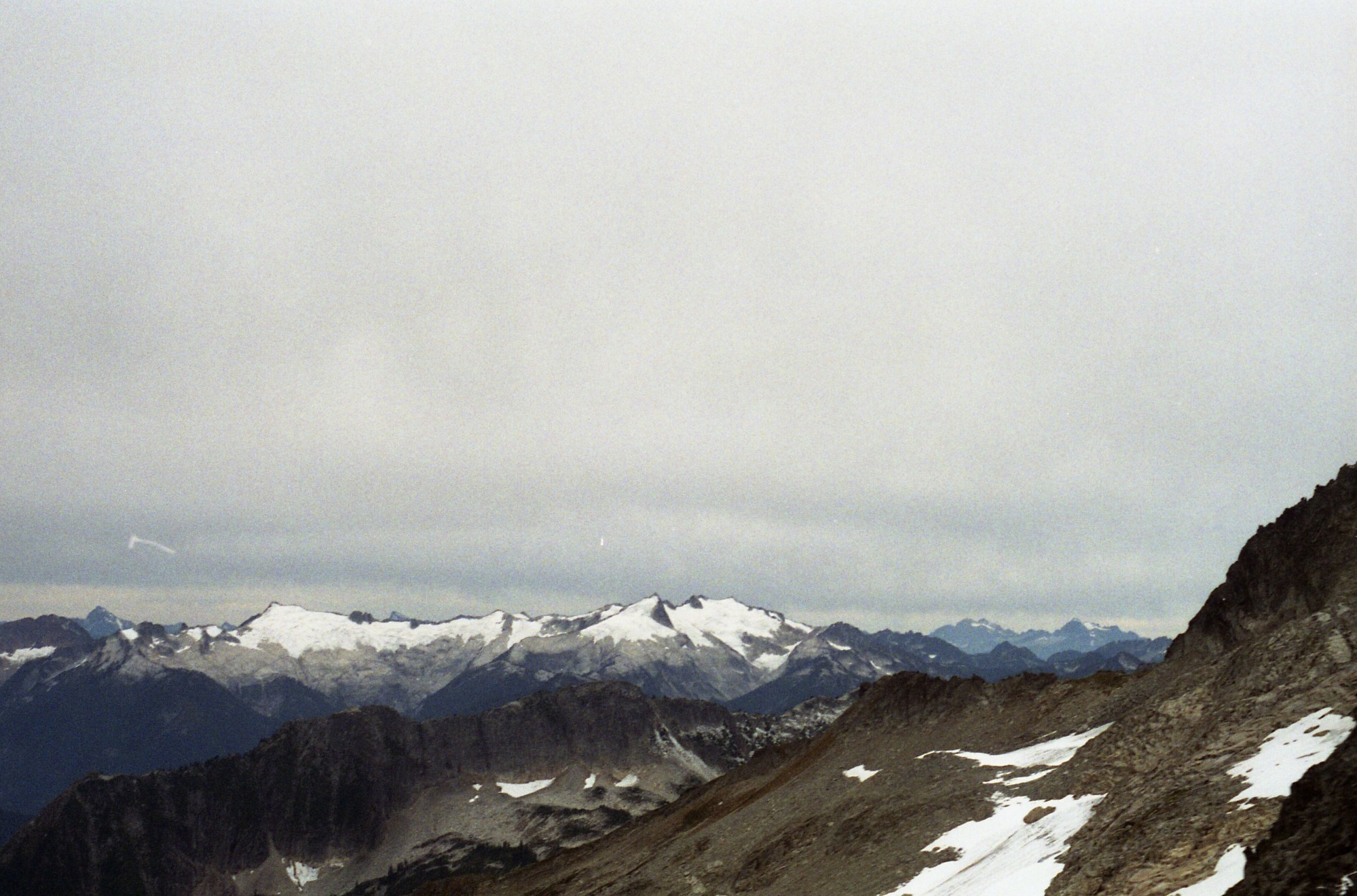 Snowy mountain ridges and peaks against a cloudy sky.