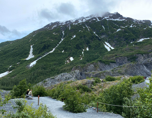 Visitors sitting on a bench on a trail on a mountain 