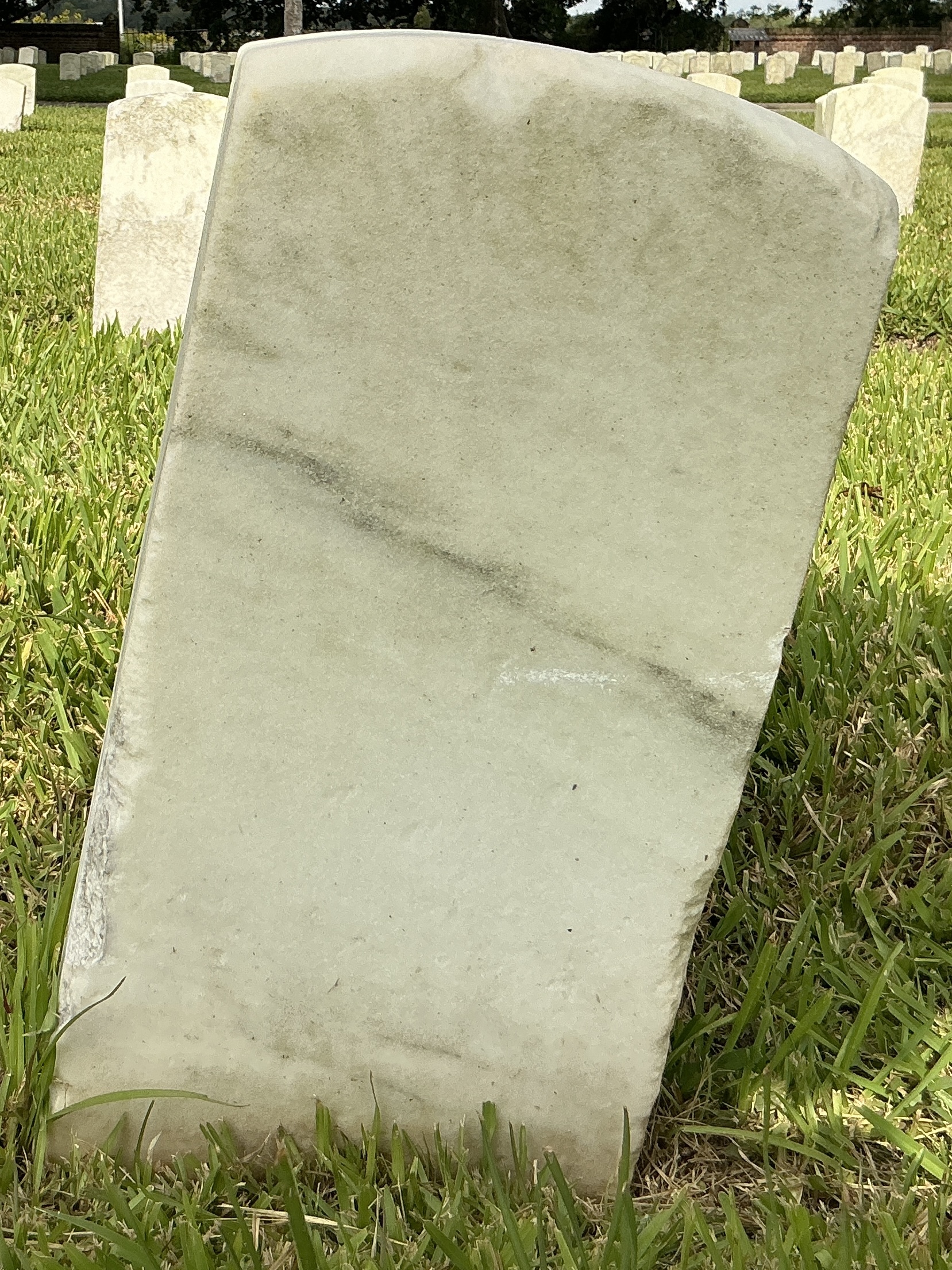 Back of historic upright marble headstone with recessed shield face.