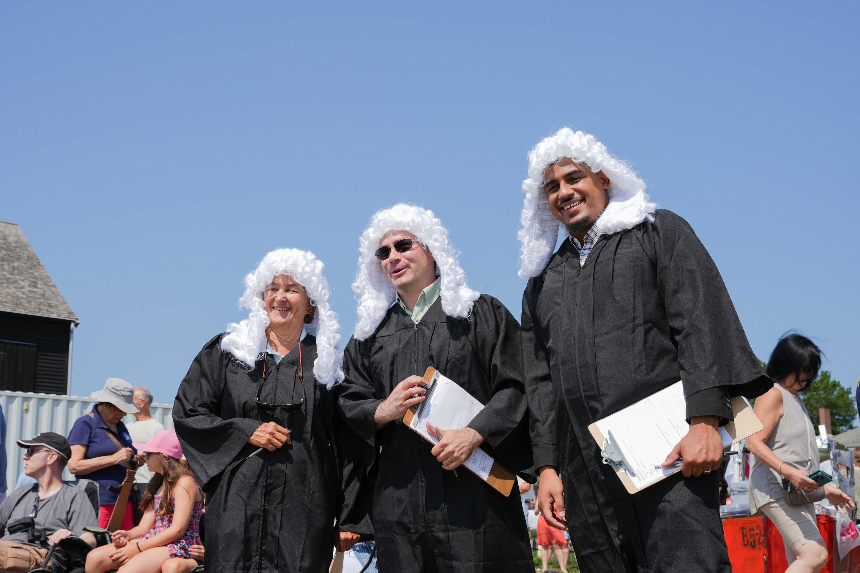 The people in historic judge uniforms smile for a picture.