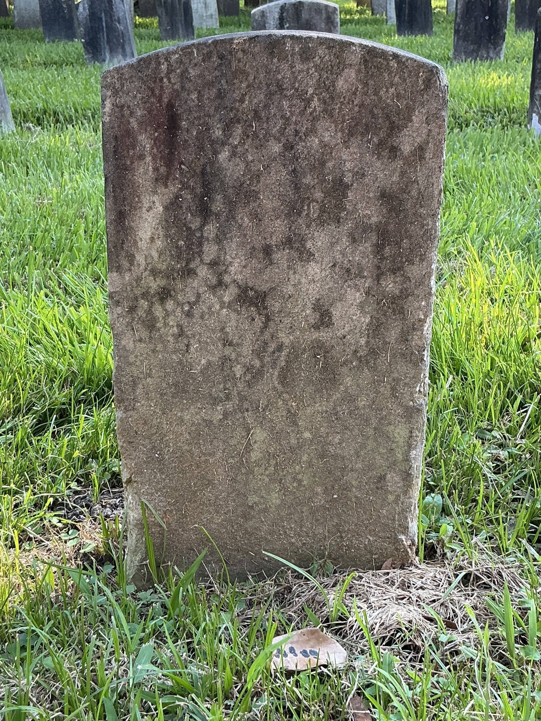 Back of historic upright marble headstone with recessed shield face.