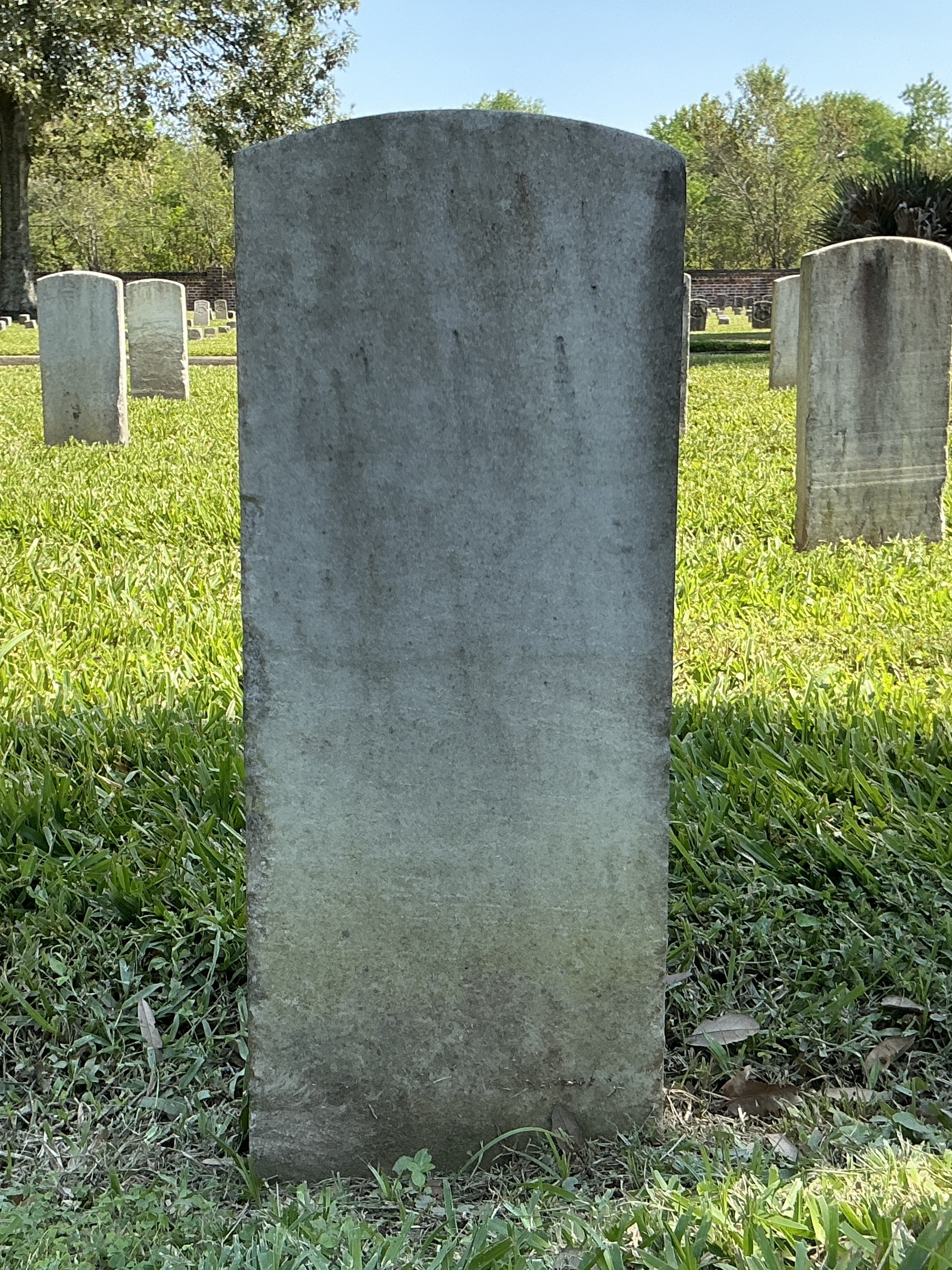Back of historic upright marble headstone with recessed shield face.