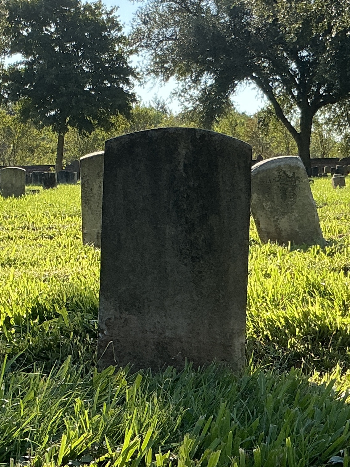 Back of historic upright marble headstone with recessed shield face.