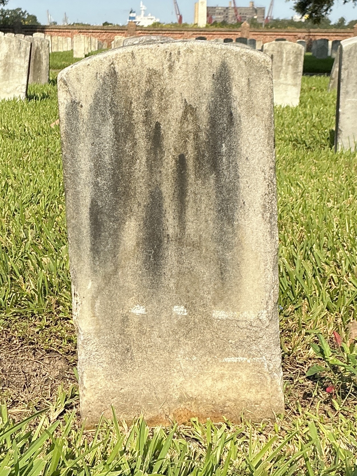 Back of historic upright marble headstone with recessed shield face.