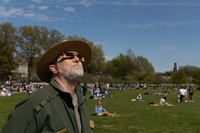 A Park Ranger looks up at a partial eclipse over the Washington Monument 