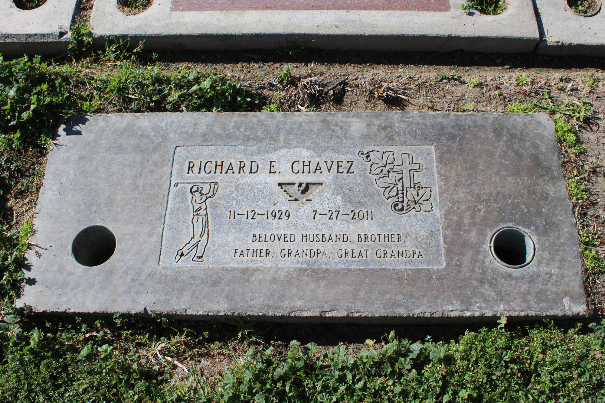 An engraved stone grave marker featuring engravings of a golfer, a huelga eagle, a cross with three leaves, a name and dates.