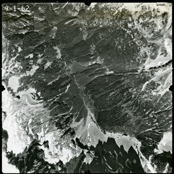 Black and white aerial photograph of glaciated mountain peaks and valleys.