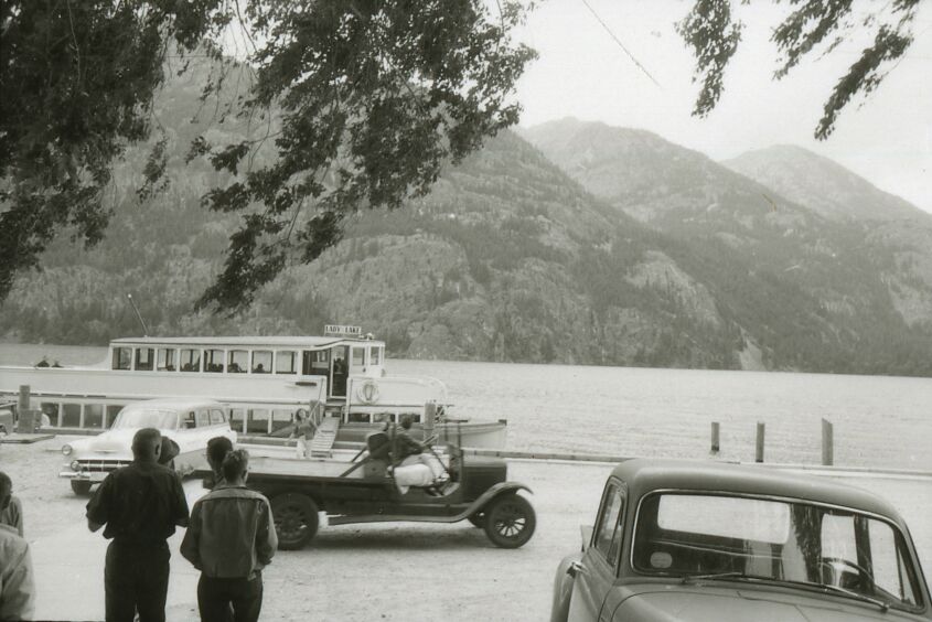 Cars and a boat next to a lake.