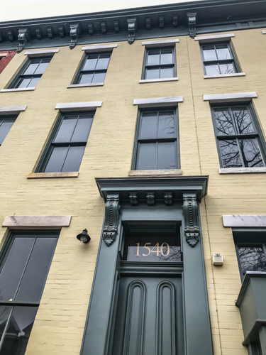 Three-story yellow townhouse with green trim