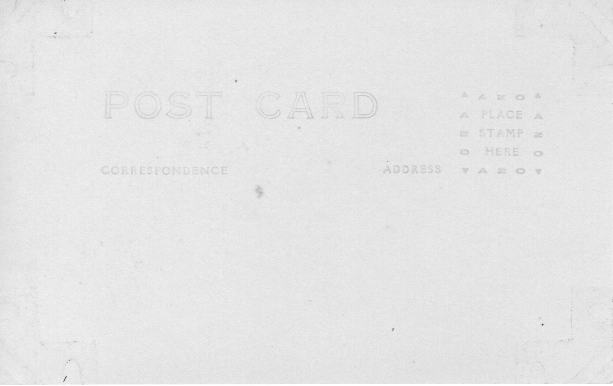 The back of a postcard. The words "Post Card" are centered on the card, along with the subtitles "Correspondence" and "Address" under it. There is a box outlined with "AZO" and triangles on each corner, with the instructions "Place stamp here" at the center. There is no address, correspondence, or stamp. Adhesive markings left by tape are on all four corners of the image. There are also a few spots from age.