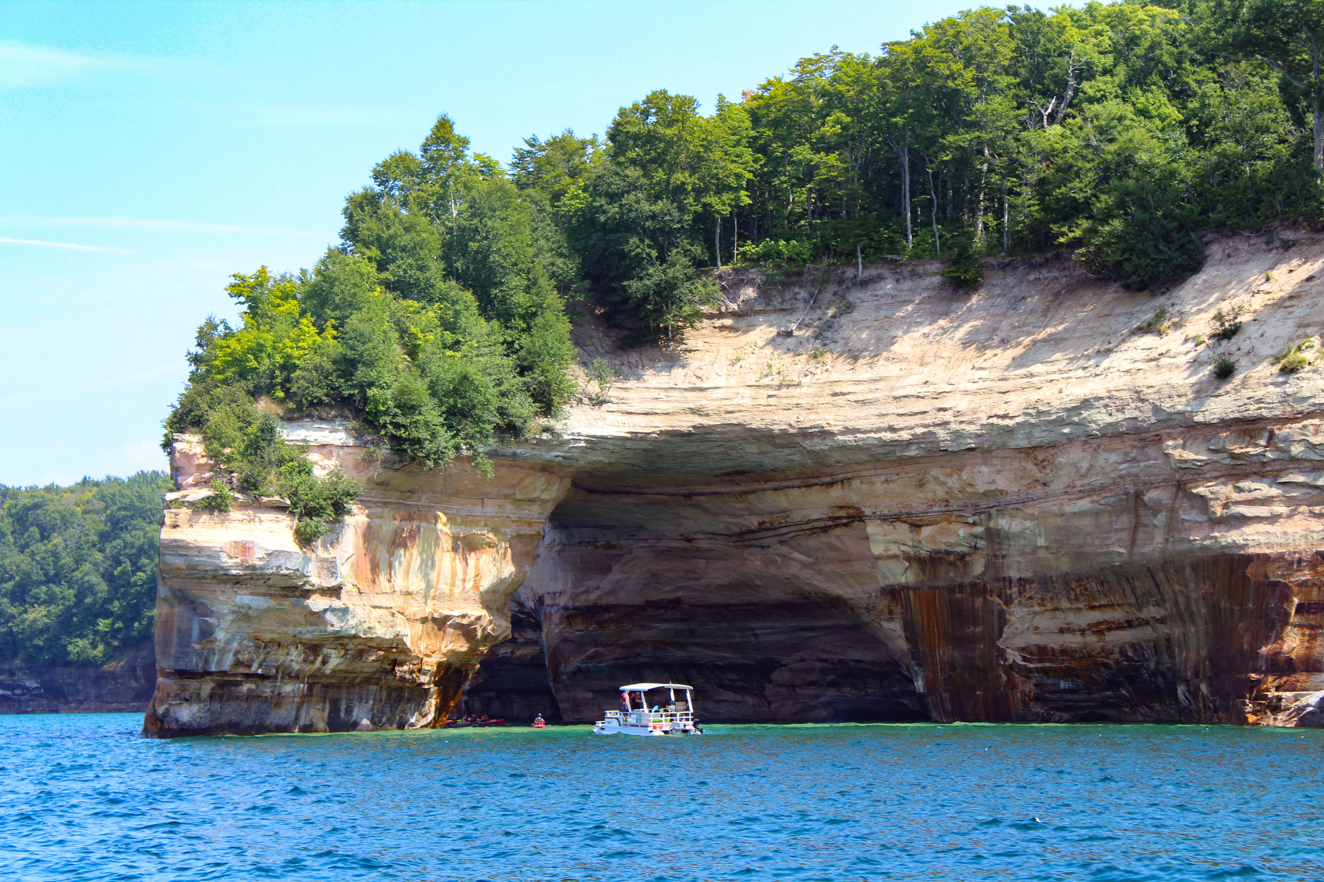 Pontoon boat near a tall cliff in a lake