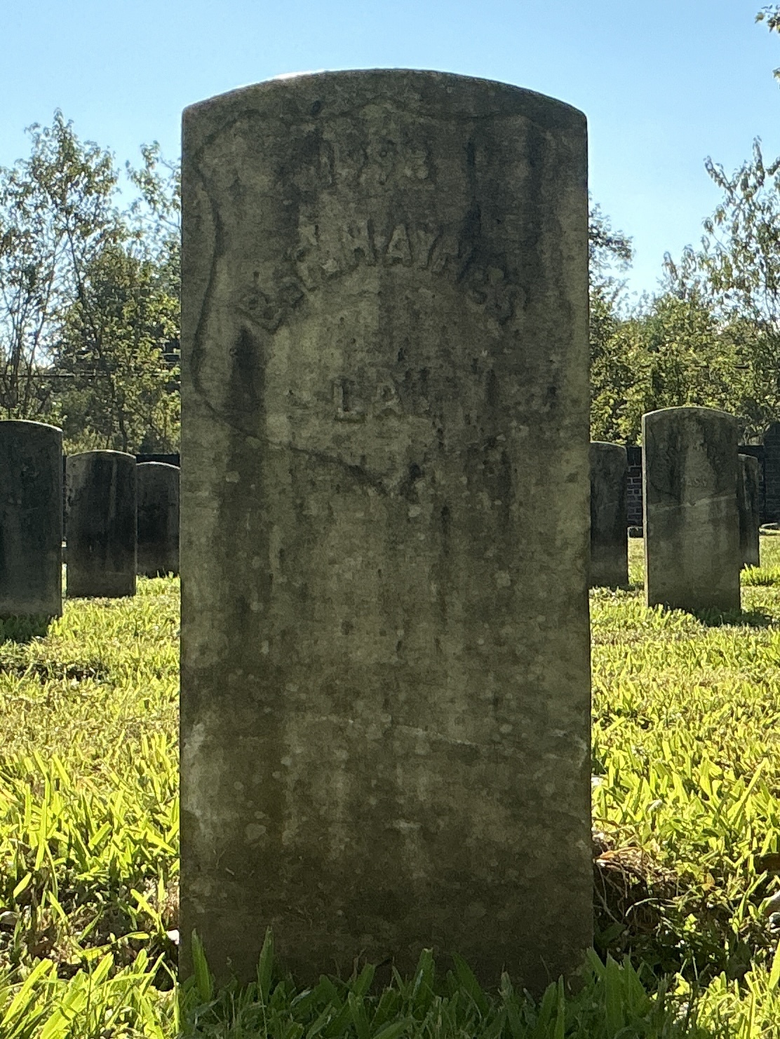 Front of historic upright marble headstone with recessed shield face.
