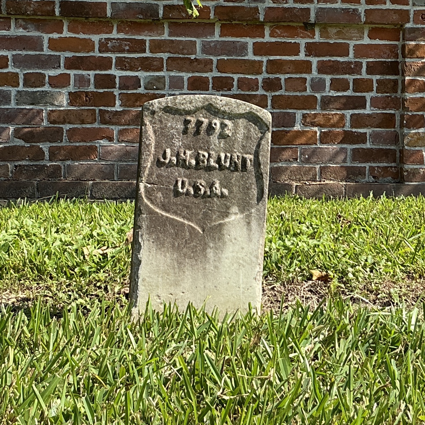 Front of historic upright marble headstone with recessed shield face.