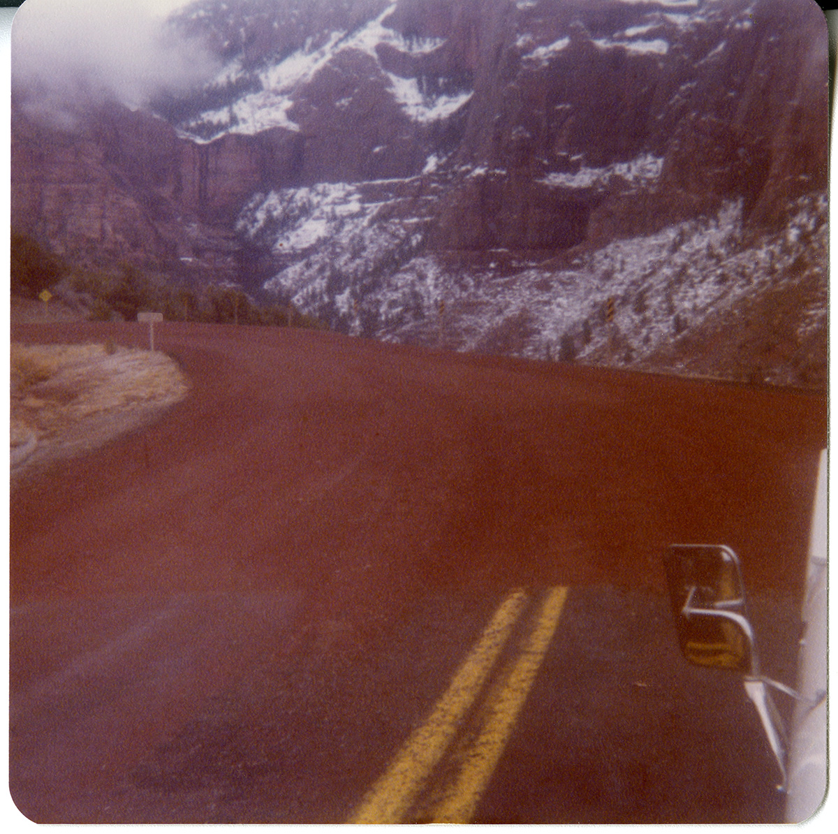 Image from car window of the Kolob Canyon Road with snow in the mountains.