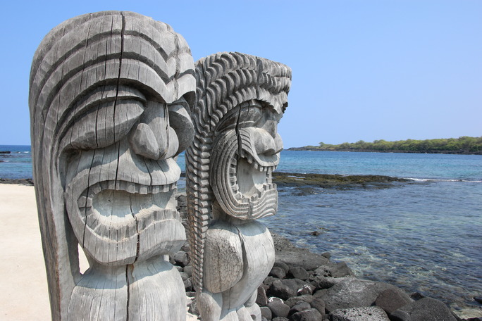 Two carved kiʻi images look out over Hōnaunau Bay.