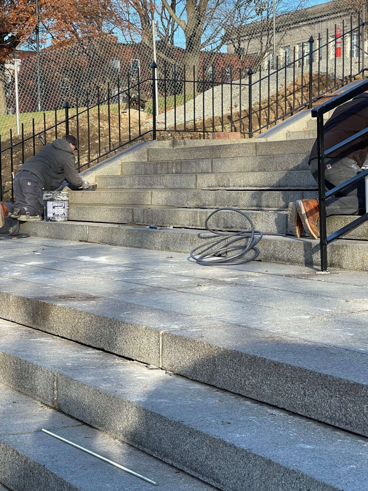 Two workers working on granite stairs on a large staircase. 
