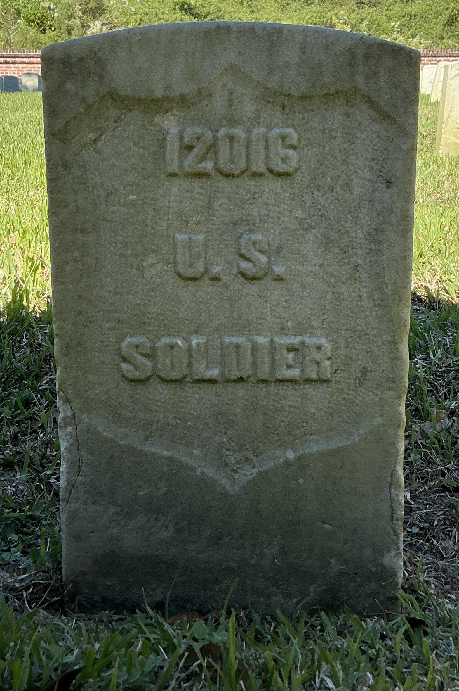 Front of historic upright marble headstone with recessed shield face.