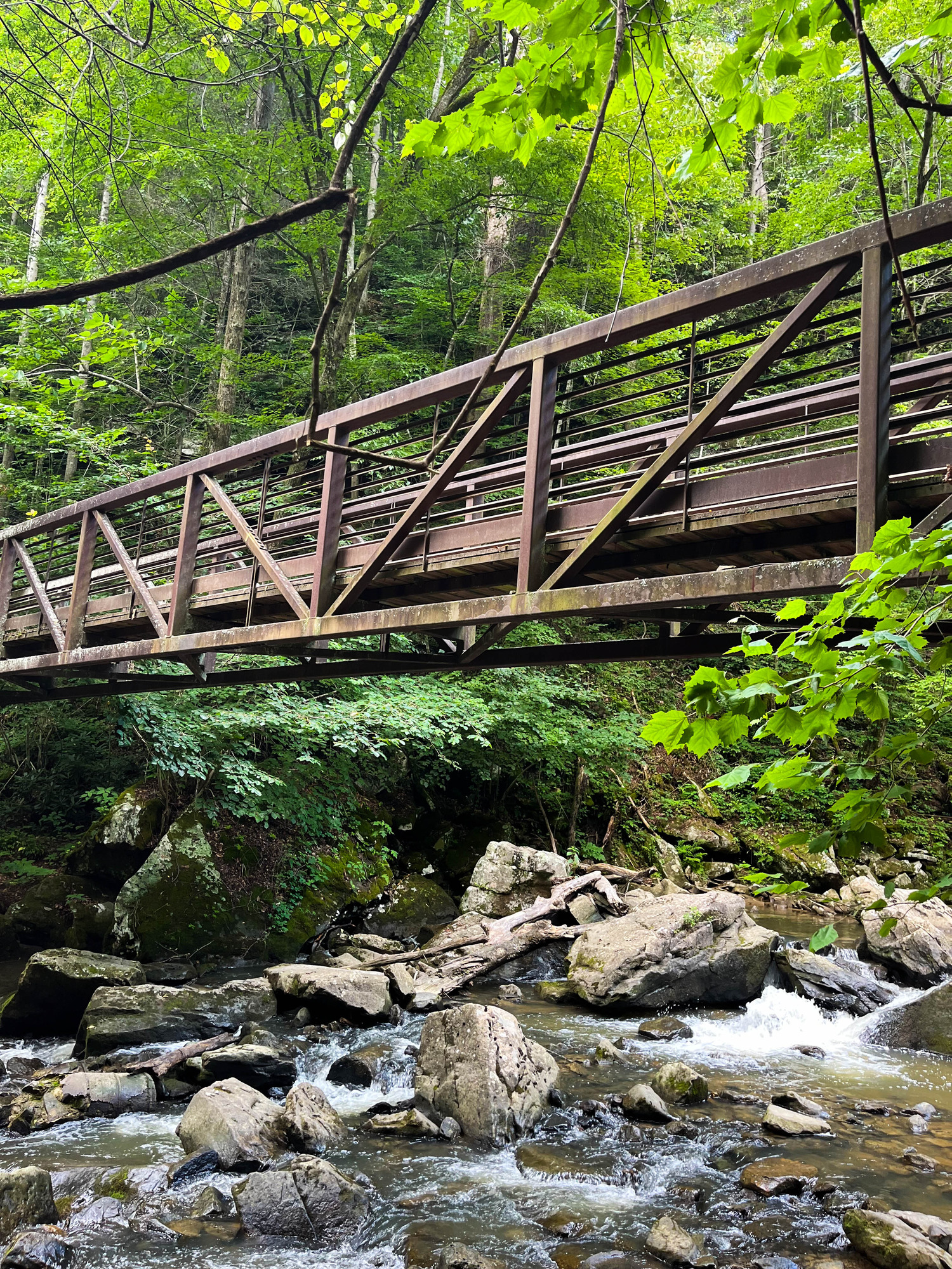 Pedestrian bridge over a rocky horizontal section of a waterfall