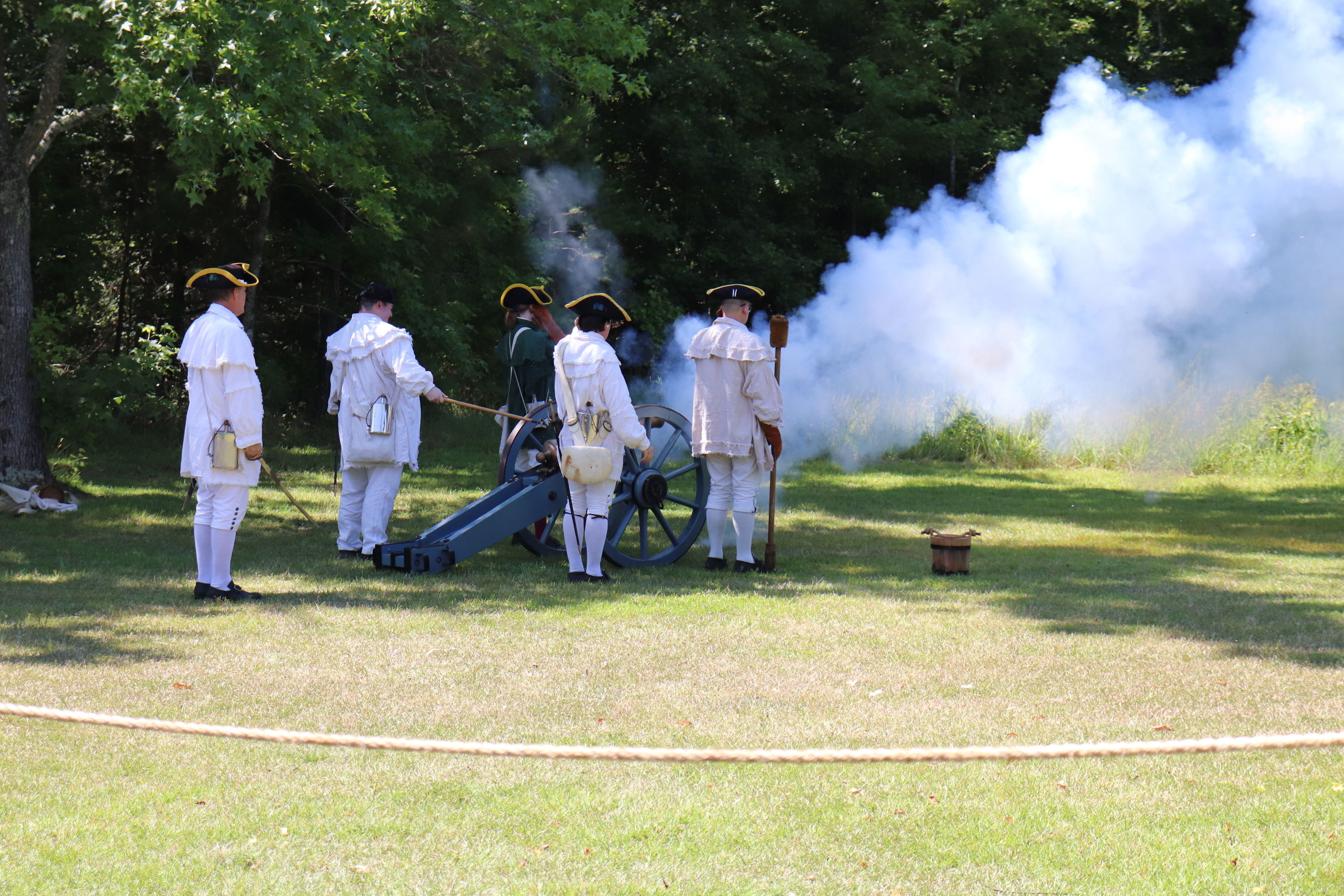 A Grasshopper cannon being fired at Cowpens. The men firing the piece are wearing period clothing and are holding various instruments to use the piece.