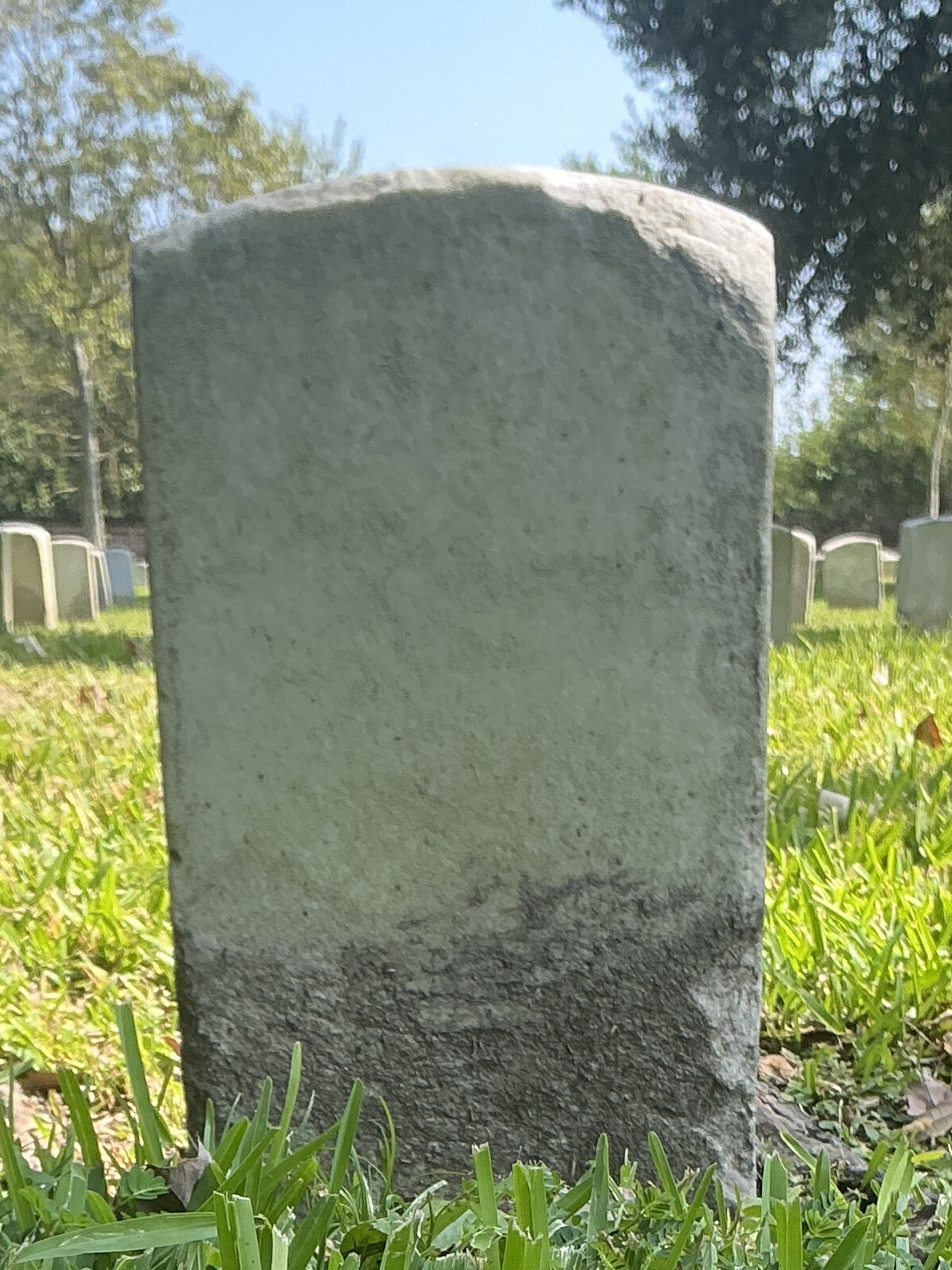 Back of historic upright marble headstone with recessed shield face.