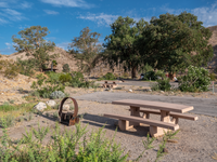 picnic bench and ground level barbecue foreground, trees and hills behind