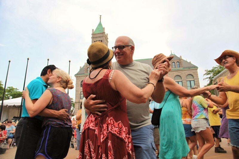 Couples dance arm in arm in an outdoor courtyard.