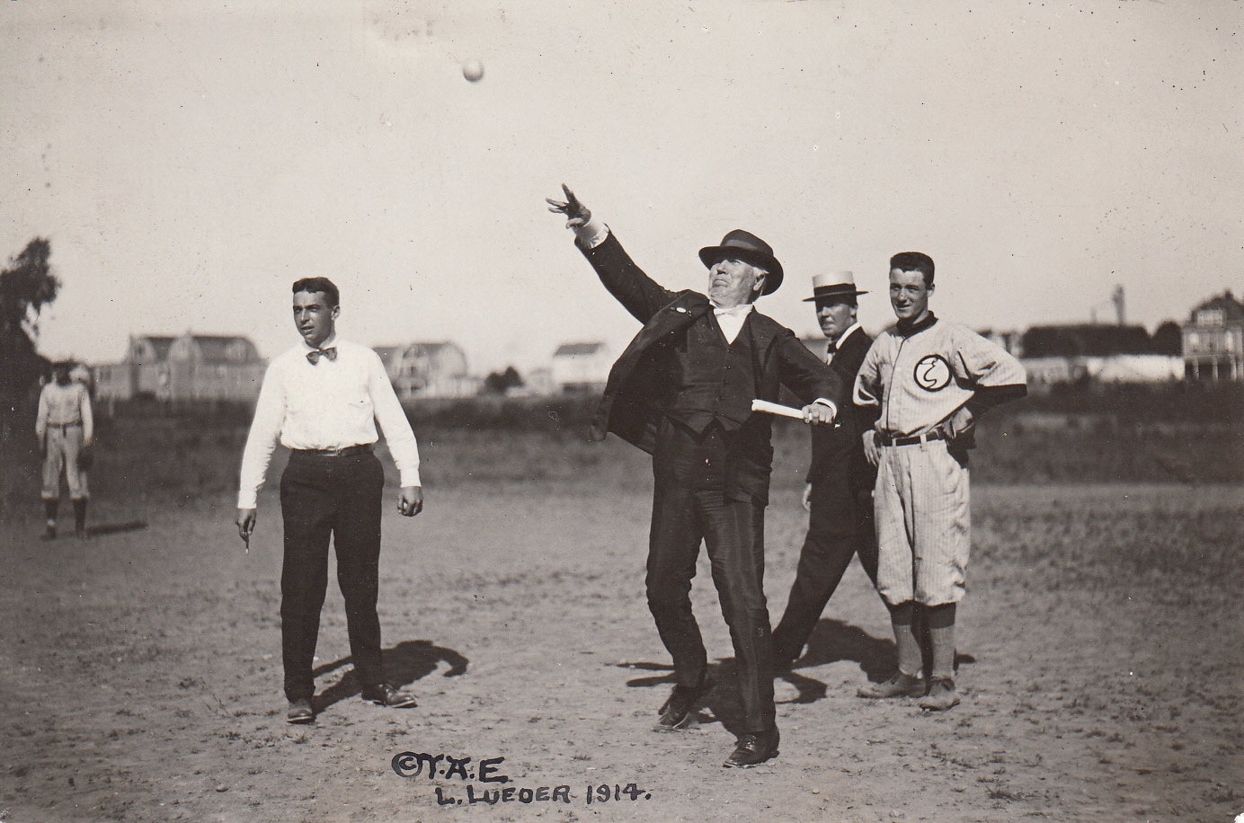Thomas Edison throwing a baseball at a company baseball game in Olympic Park, Len McChesney and Peter Schwobel standing next to Edison.