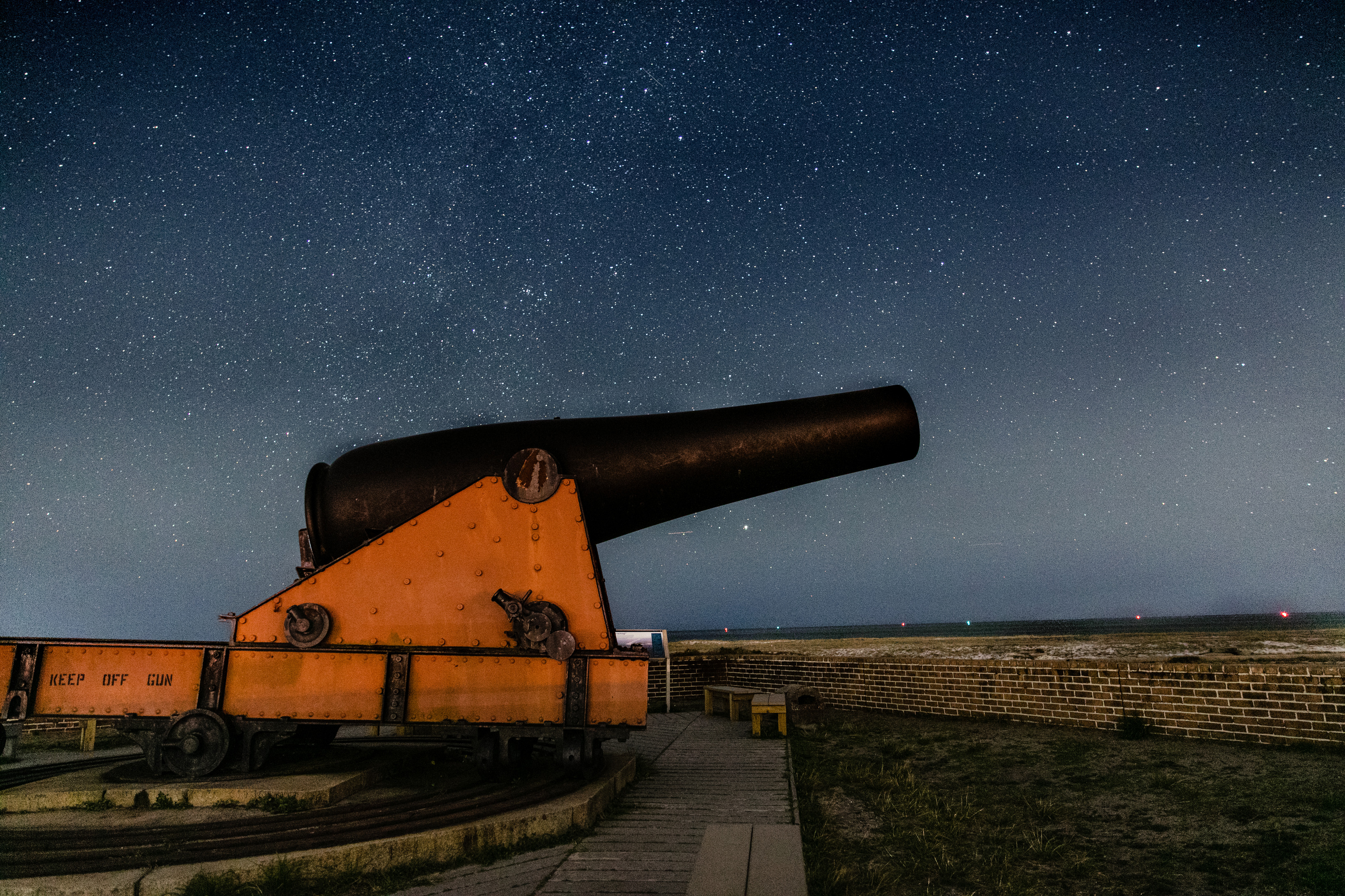 A cannon atop Fort Pickens stands in front of a starry night sky.