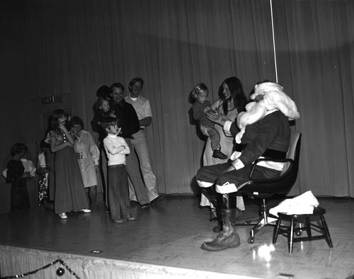 Christmas holiday party, 1976. Children and parents wait in line to talk to Santa on stage in the Visitor Center auditorium.