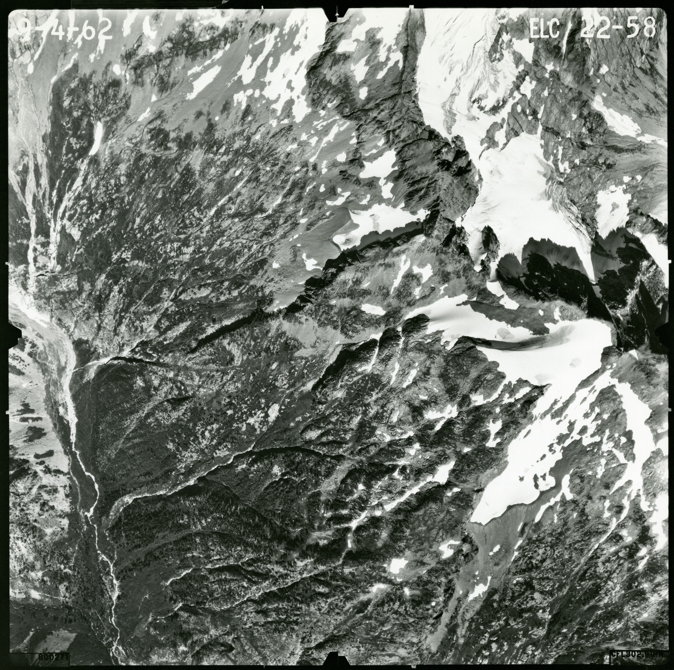 Black and white aerial photograph of glaciated mountain peaks and valleys.