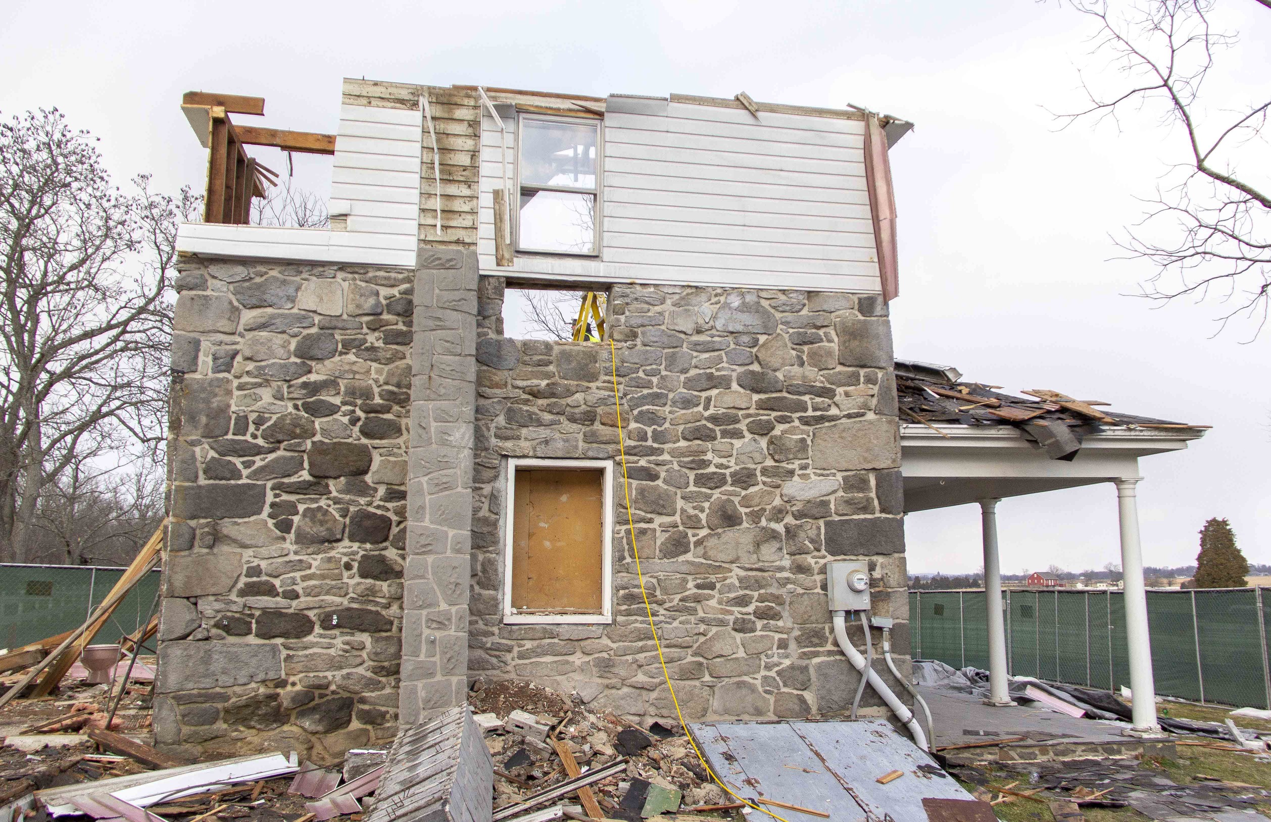 Hired contractors finish the selective demolition process on the modern additions of the house. This is a side view of the house. The repaired historic window is in the center of the original masonry structure. The second floor modern white siding remains only on this side of the house. The front porch is to the right. 