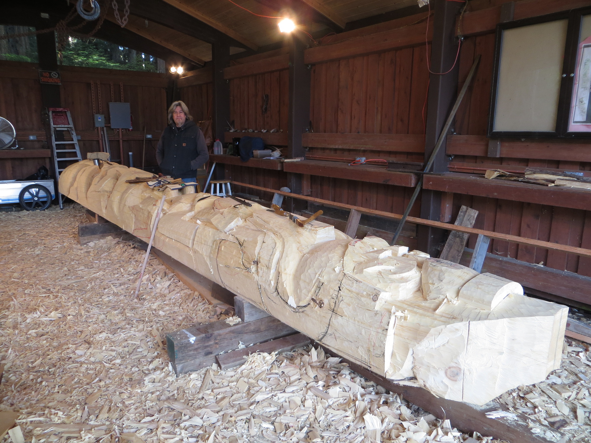 Tommy Joseph stands at the totem pole he is carving. 