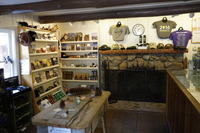 A stone fireplace sits inside a white walled building. To the left are souvenir items