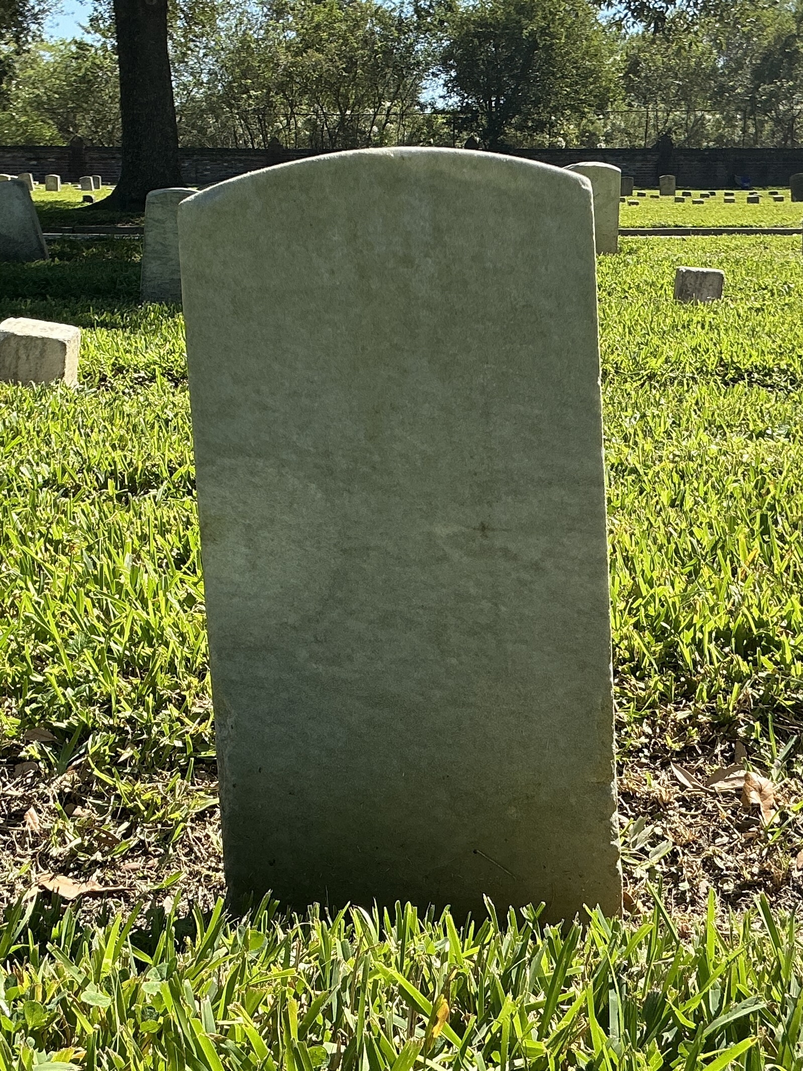 Back of historic upright marble headstone with recessed shield face.