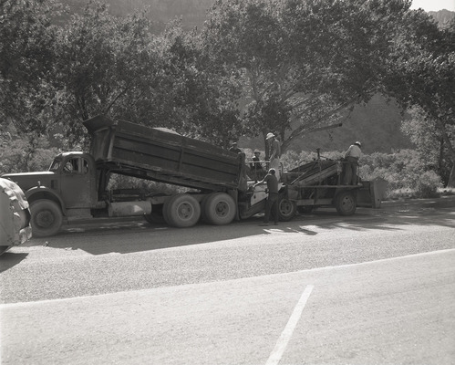 Men operating sealcoating machine while sealcoating parking area in Zion.