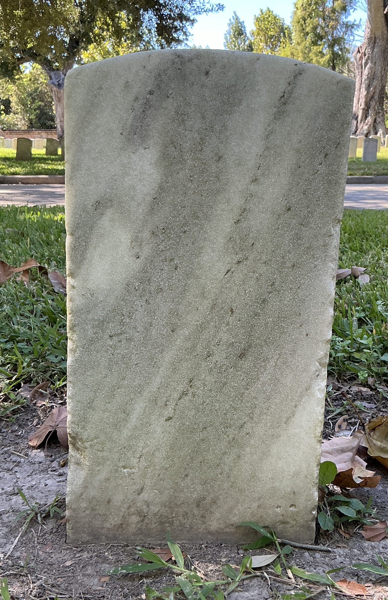 Back of historic upright marble headstone with recessed shield face.